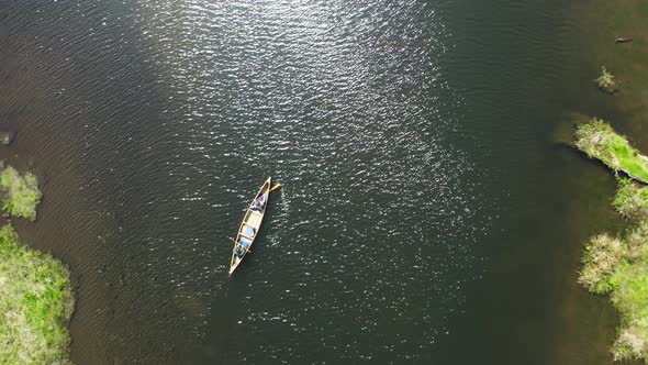 Top down drone shot of two people paddling a canoe in an estuary