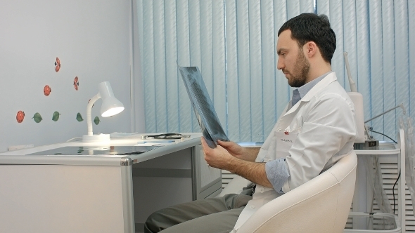 Male Doctor Or Dentist Looking At X-ray