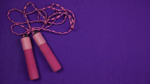 Unrolling Purple Yoga Mat and Pink Skipping Rope on it. Stop Motion