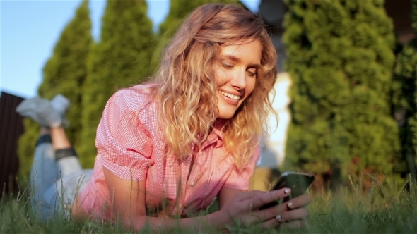 Beautiful Girl Laying On Grass, Using Mobile Phone