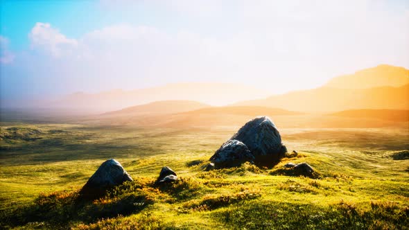 Meadow with Huge Stones Among the Grass on the Hillside at Sunset