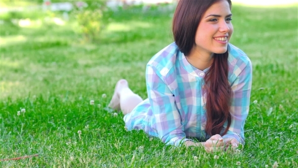 Beautiful Smiling Girl Lying On a Grass Outdoor. alt