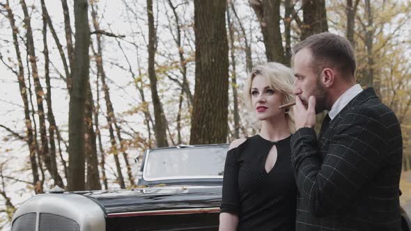 Portrait of Glamorous Couple Smoking Cigar and Looking in the Distance