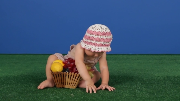 Child Next To A Basket Of Juicy Fruits