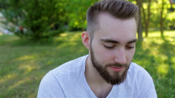Casual Young Man Using a Phone In The Park alt