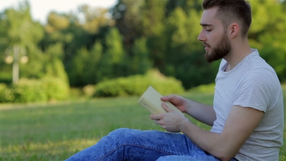 Young Man Reading a Book On The Grass alt