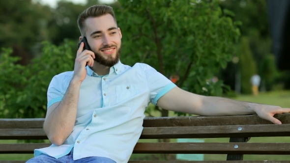 Smiling Handsome Man Talking On The Phone In Park alt