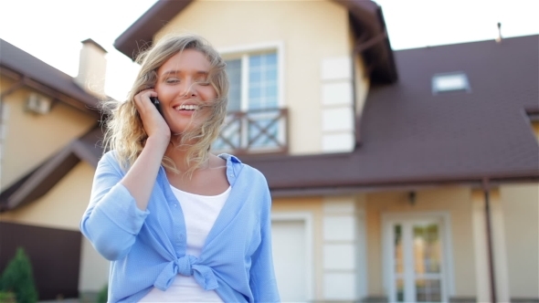 Beautiful Girl Talking On Phone Next To New House alt