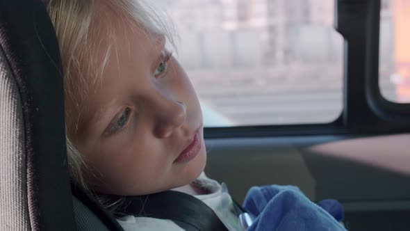 Tired little girl in car safety seat