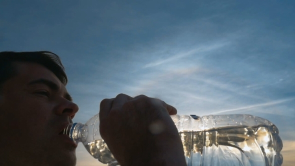 Man Drinking Fresh Water From The Bottle At Sunset