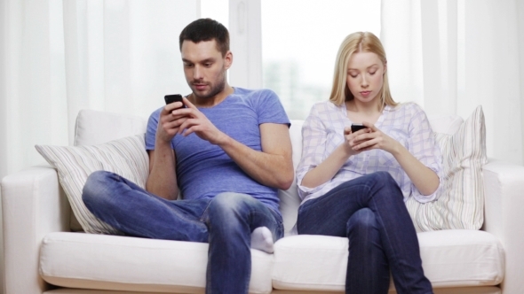 Concentrated Couple With Smartphones At Home
