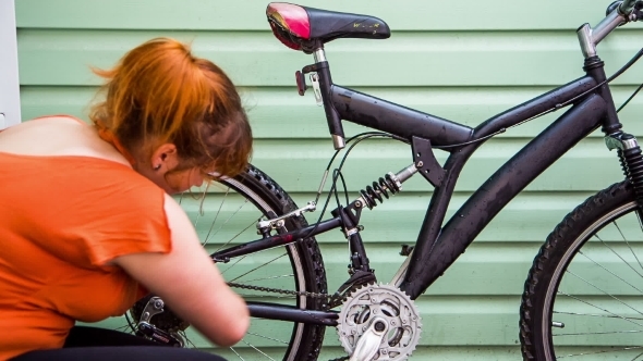 Young Girl Washing The Bicycle At Green Wall