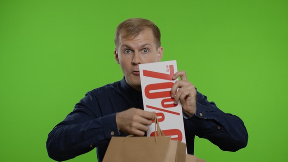 Man Taking Out Sale Discounts Inscription From Shopping Bags, Smiling Satisfied with Low Prices