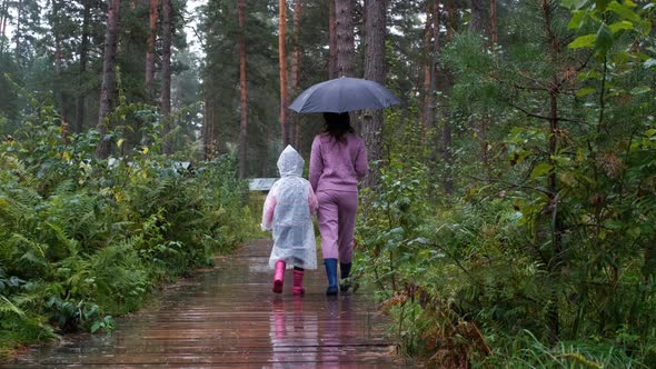 Little Girl with Mom Enjoying Walking in the Rain