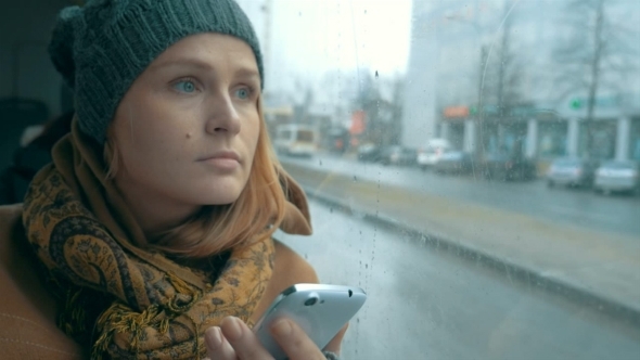 Woman Using Phone In Bus On Rainy Day