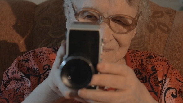 Senior Woman Filming With Retro Video Camera alt
