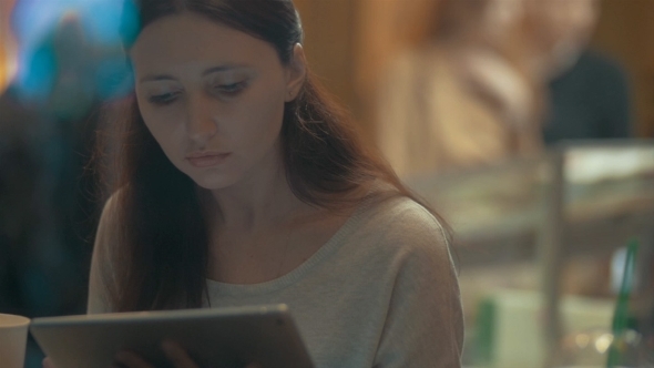Woman Browsing The Internet On Pad In Cafe alt