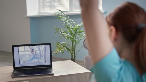 Woman Leading Sporty Lifestyle Performs Physical Exercises From Video Lessons on Laptop in Living
