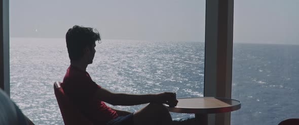 Man having a coffee sitting at the bar of a moving ferryboat