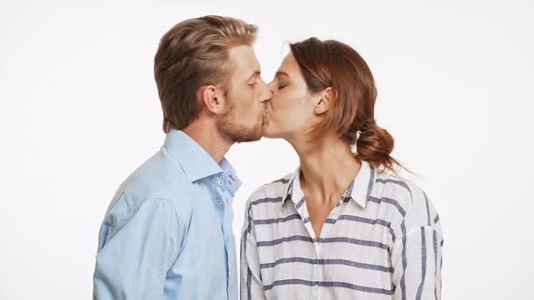 Beautiful Caucasian Couple Surprisingly Kissing on White Background in Slowmotion