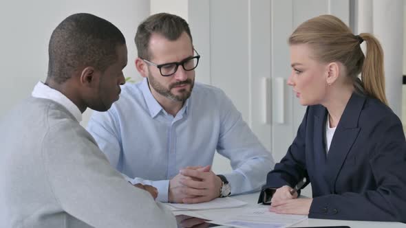 Businesswoman Explaining Documents to Male Colleagues