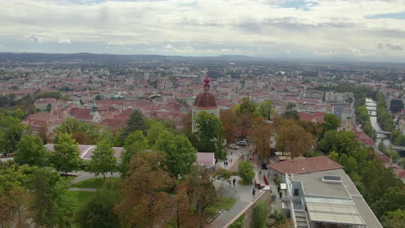 Aerial orbit view flying around landmark Glokenturm tower on Graz's Schloßberg hilltop woodland park