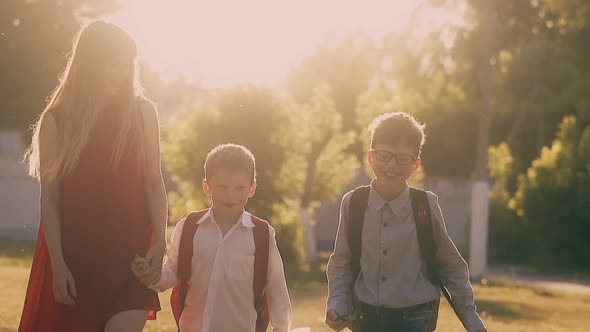 Schoolboys and Beautiful Woman in Red Walk After Lessons