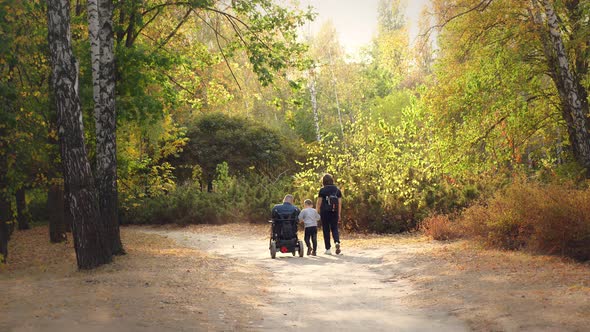 Wheelchair Man. Handicapped Man. Young Disabled Man in an Automated Wheelchair Walks with His Family