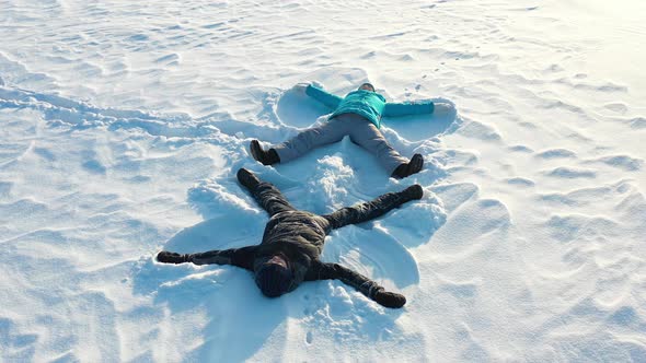 A Family Makes a Figure of a Snow Angel in a Clearing in the Forest