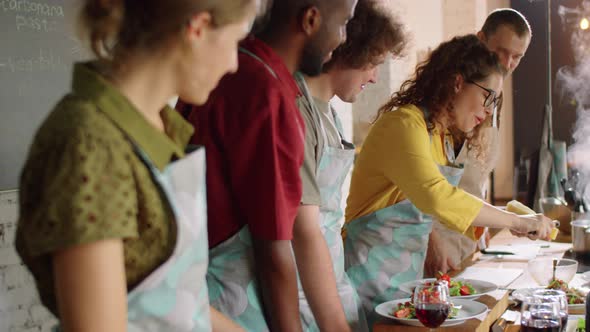 Woman Grating Cheese on Salad during Cooking Master Class