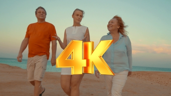 Young Woman And Parents Walking On Beach