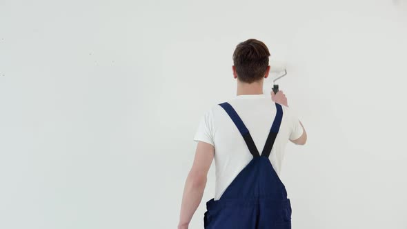 Painter with a Roller in His Hands Paints a White Wall