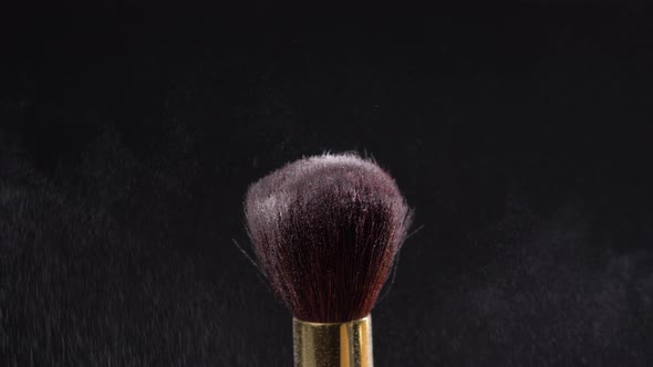 Two Makeup Brushes with Powder on a Dark Background