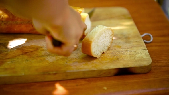 Baker Slicing French Bread On a Cutting Board