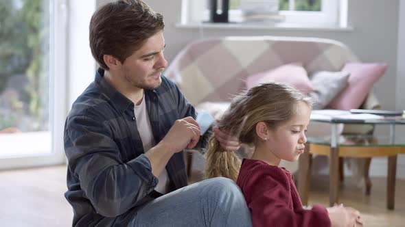 Side View Portrait of Loving Single Father Combing Curly Hair of Cute Little Girl at Home in the