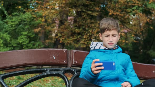 Boy Sits On Bench In A Park