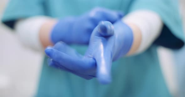 Female Surgeon Putting on Protective Gloves