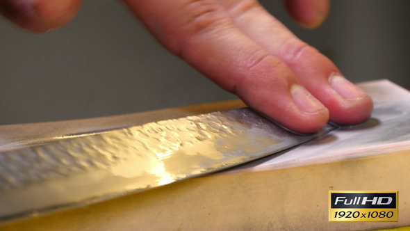 Sushi Chef Sharpening his Knife Blade with a Stone