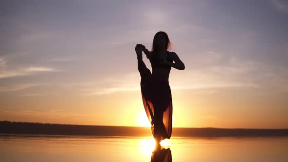Silhouette Yoga Woman Practicing Yoga Posture on Sea Coast at Beautiful Sunset