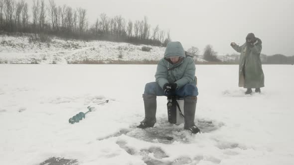 Fishermen are fishing on frozen river at winter fishing.