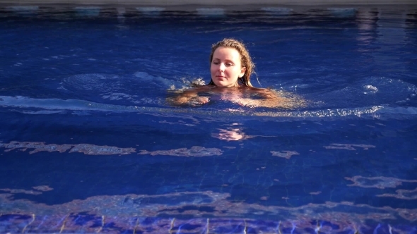 Young Woman Swimming In Blue Water Pool On