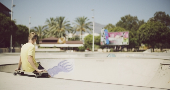 Solitary Teenage Boy Sitting On a Longboard