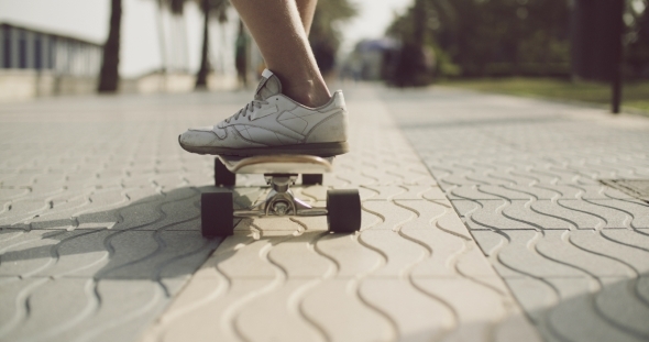 Feet Of a Man Riding On a Longboard In The Street