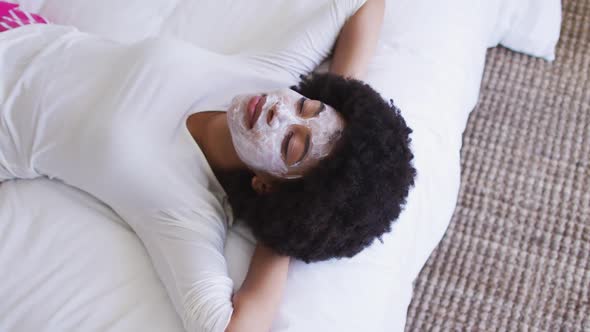 African american woman wearing face mask laying on the bed