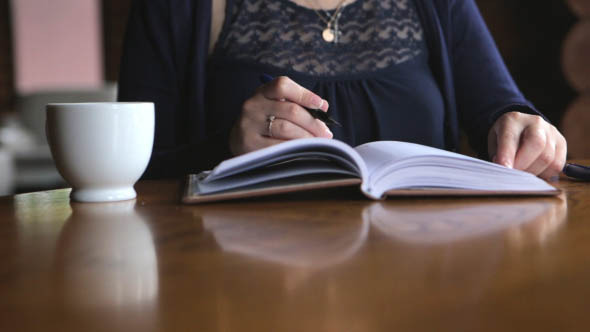 Woman Makes Notes in a Diary