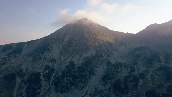 Flying up toward the summit of a majestic mountain with clouds at the top.