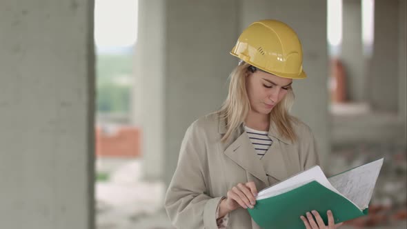 Young Female Architect Construction Engineer at a Construction Site Eximaining Documents