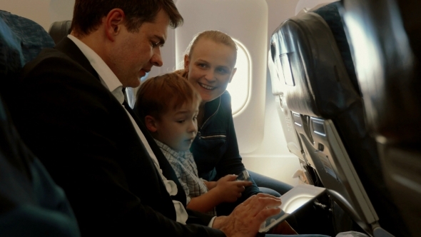Family Of Three In Plane With Smartphone