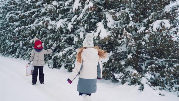 A Little Boy Waiting for a Girl Who Runs to Him on the Background of a Winter Forest