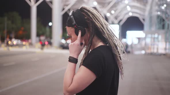 Young Attractive Hipster Woman Use Smartphone Listening Music and Dance on Street at Night